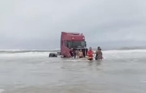 Caminhão atolado na água do mar.