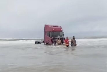 Caminhão atolado na água do mar.