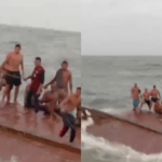 Paasageiros em cima do barco virado, aguardando resgate