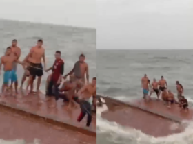 Paasageiros em cima do barco virado, aguardando resgate