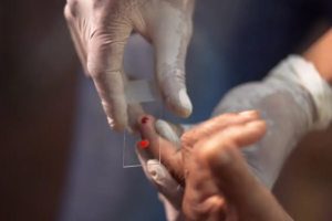 duas mãos, realizando coleta de sangue para exame de malária