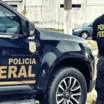 Imagem ilustrativa de agente da Polícia Federal ao lado de viatura