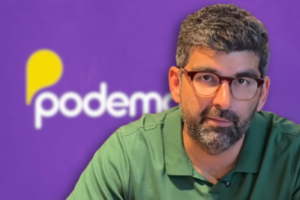 Dr. Daniel. No fundo, imagem da logo do Podemos