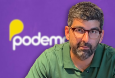 Dr. Daniel. No fundo, imagem da logo do Podemos