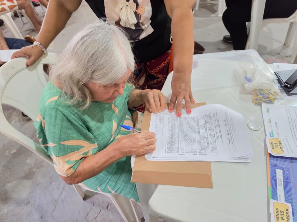 Moradora assina documento de título de terra em Belém.