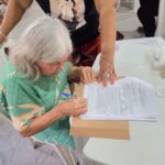 Moradora assina documento de título de terra em Belém.