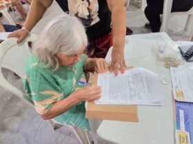 Moradora assina documento de título de terra em Belém.