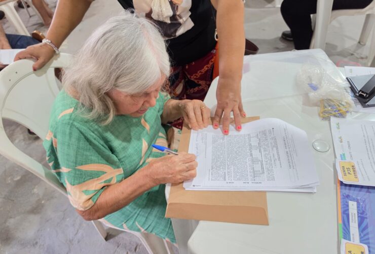 Moradora assina documento de título de terra em Belém.