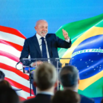 Presidente lula em pé com a bandeira do brasil e do EUA atras
