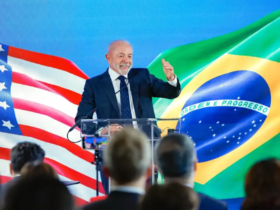 Presidente lula em pé com a bandeira do brasil e do EUA atras