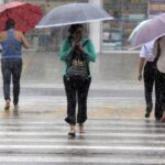 Pessoas enfrentando chuva forte em Belém
