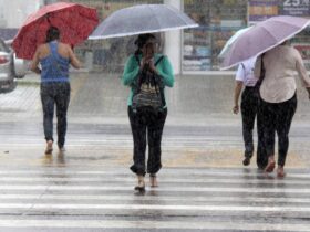 Pessoas enfrentando chuva forte em Belém